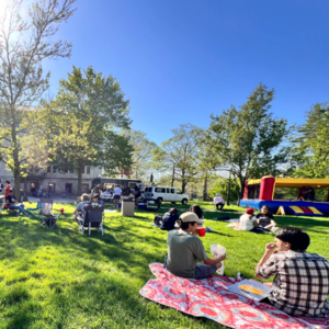 Students sit on blankets on lawn near bouncy house and food truck at Galvin Scholars Year-End Event