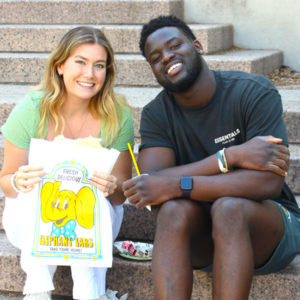 Two students pose with takeout bag from elephant ear and lemonade food truck at Galvin Scholars Year-End Event